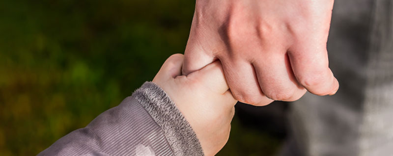 Child holding onto parent's finger